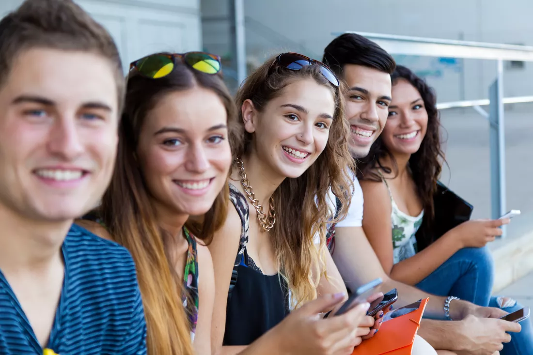 group-students-having-fun-with-smartphones-after-class